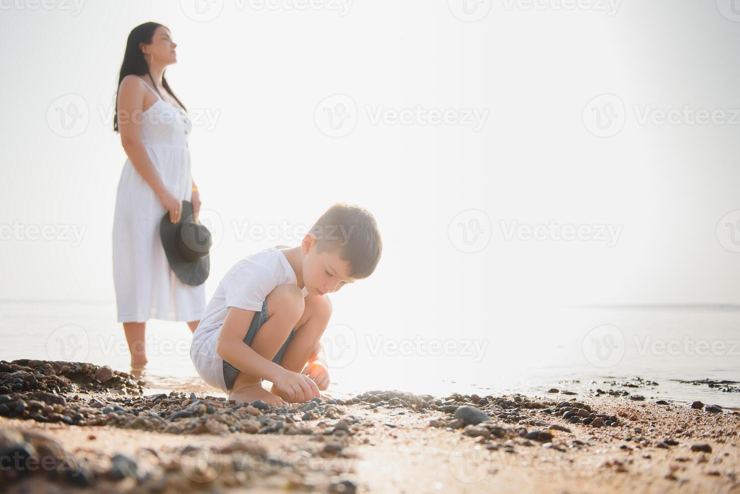Mother and son playing on the beach at the day time. Concept of friendly family. photo