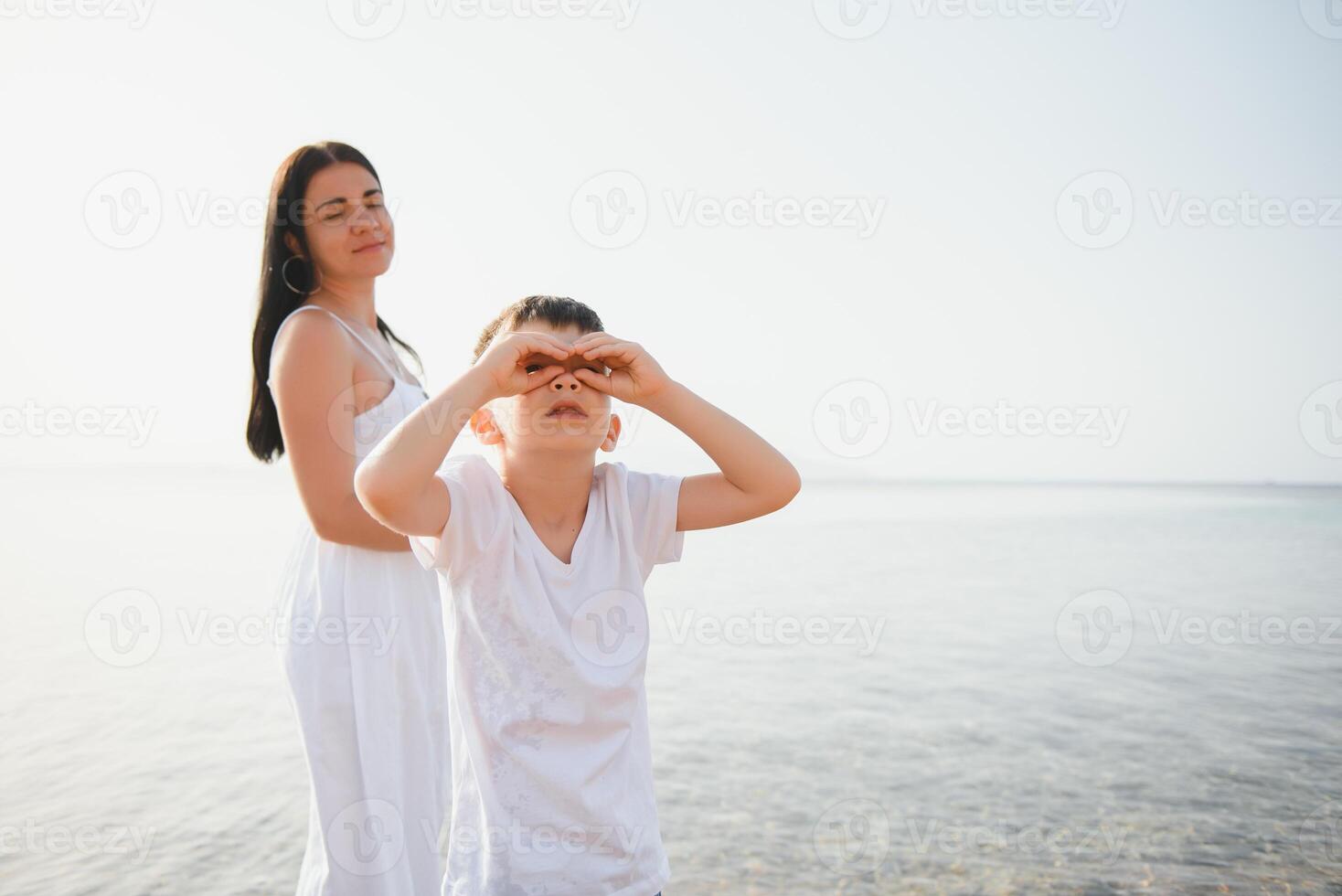 Happy mother and son walk along the ocean beach having great family time on vacation on Pandawa Beach, Bali. Paradise, travel, vacation concept photo