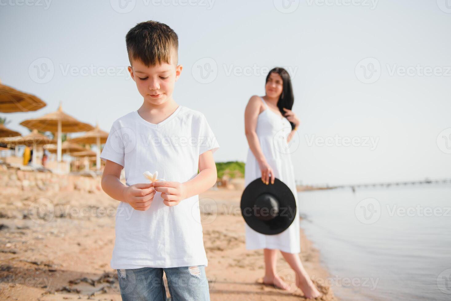 Mother and son playing on the beach at the day time. Concept of friendly family. photo
