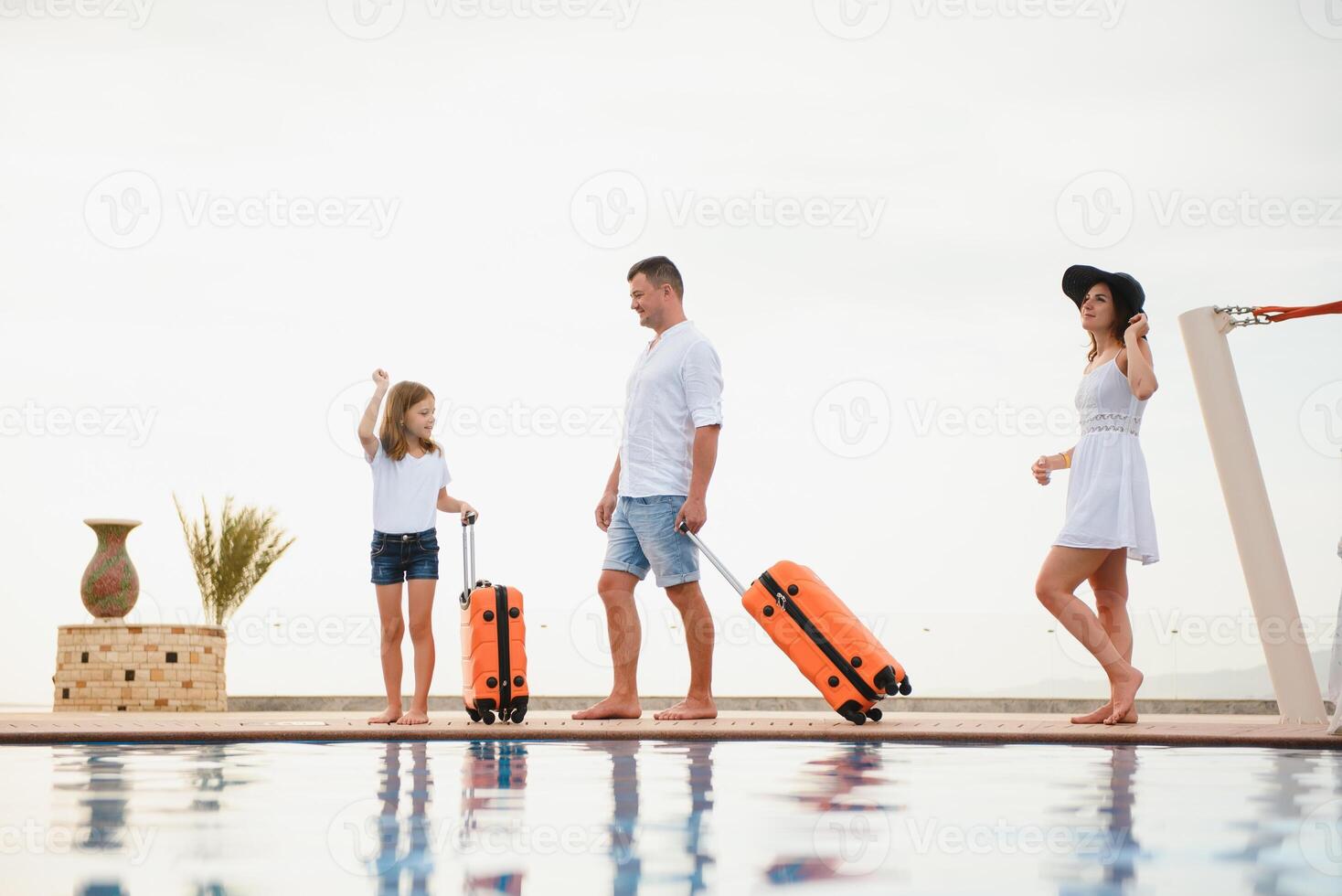 young family with suitcases walking to hotel building with beautiful swimming pool. traveling and relaxing time concept. photo