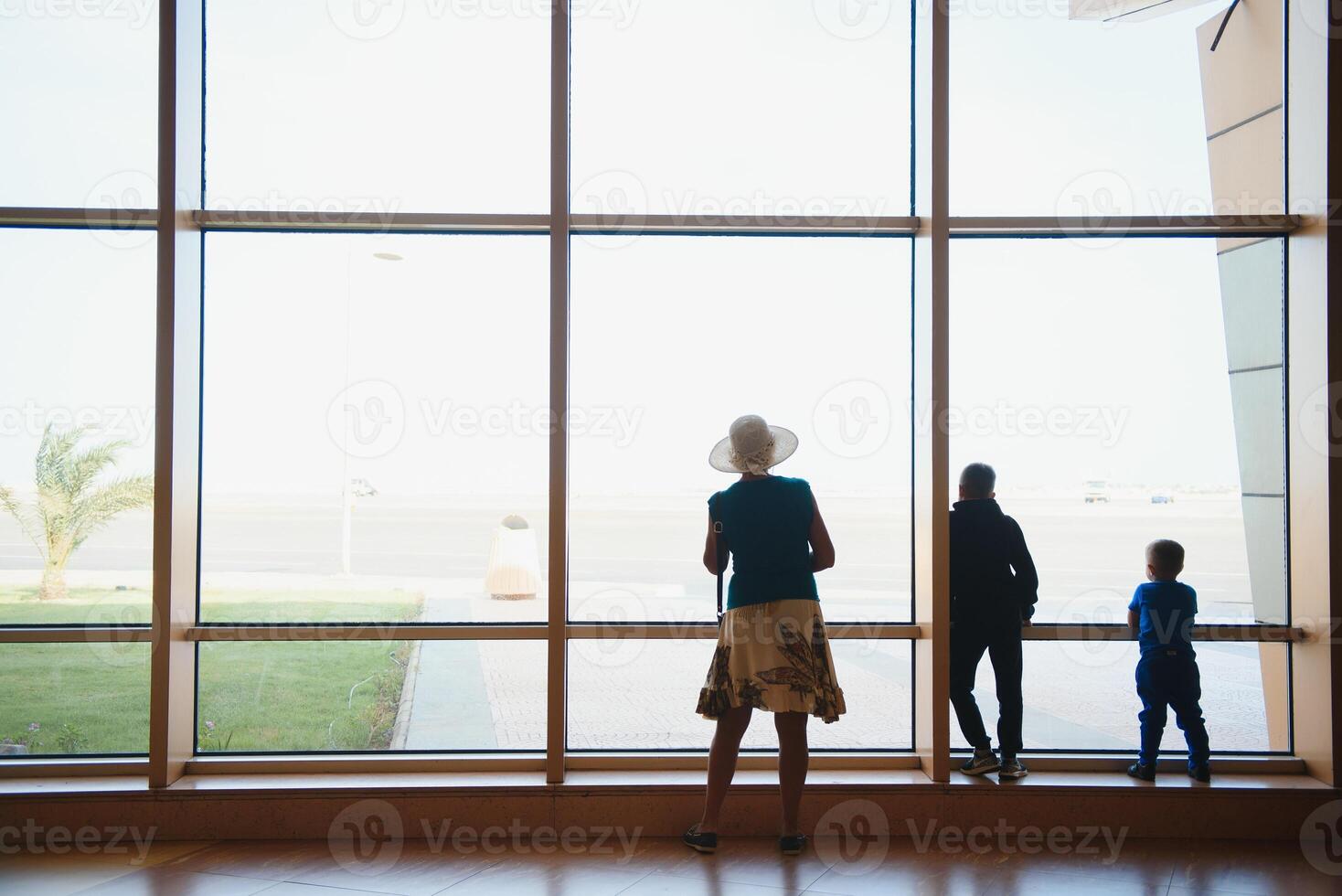 Family at airport before flight. Mother and kids waiting to board at departure gate of modern international terminal. Traveling and flying with children. Mom with baby and toddler boarding airplane. photo