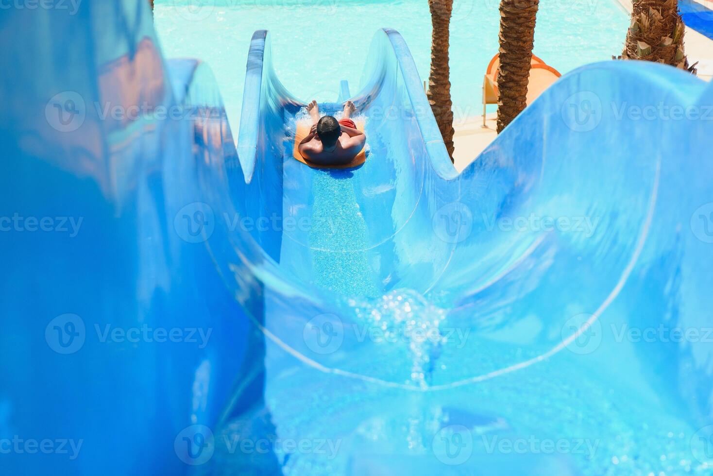 little boy sliding on the swimming pool photo