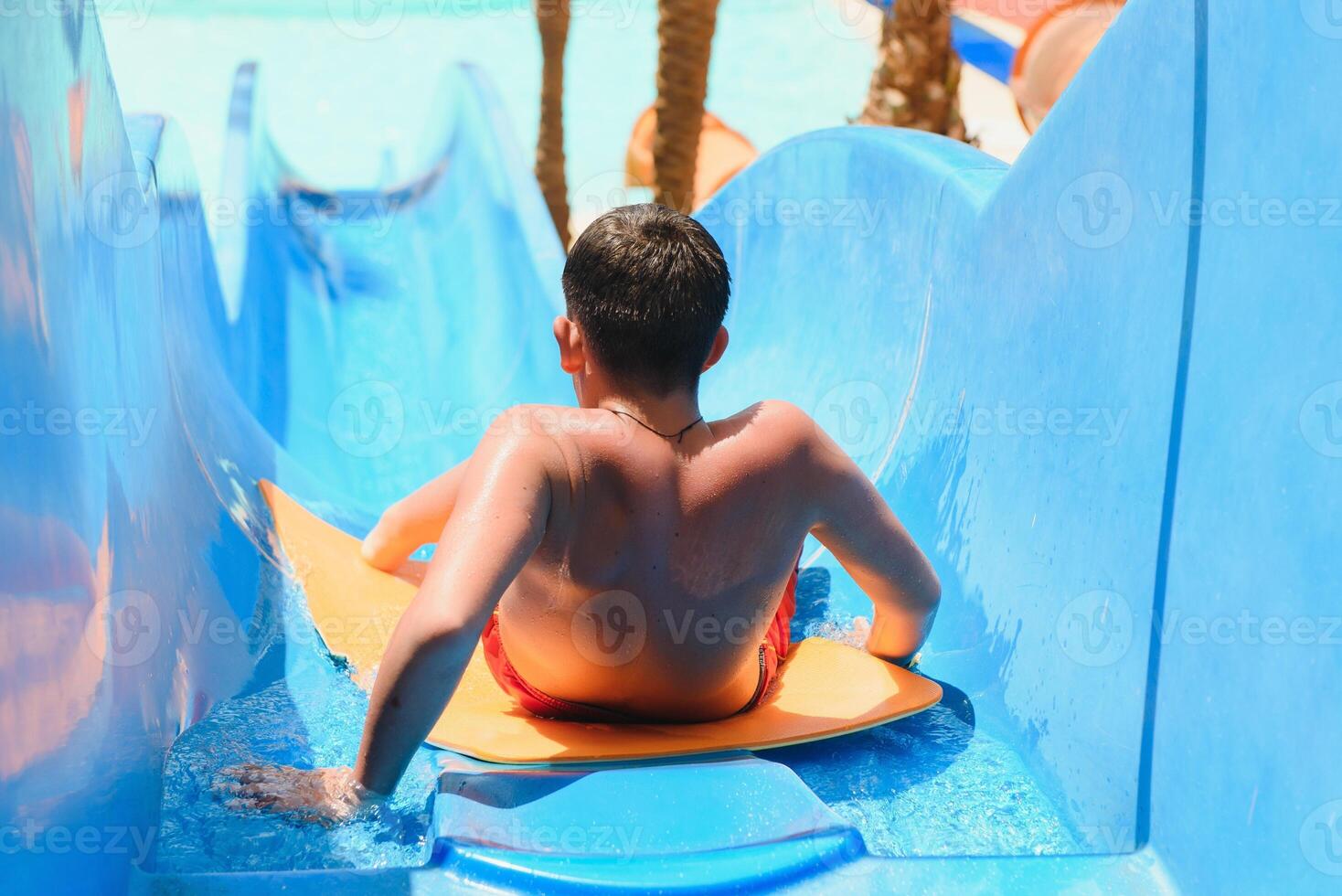 little boy sliding on the swimming pool photo