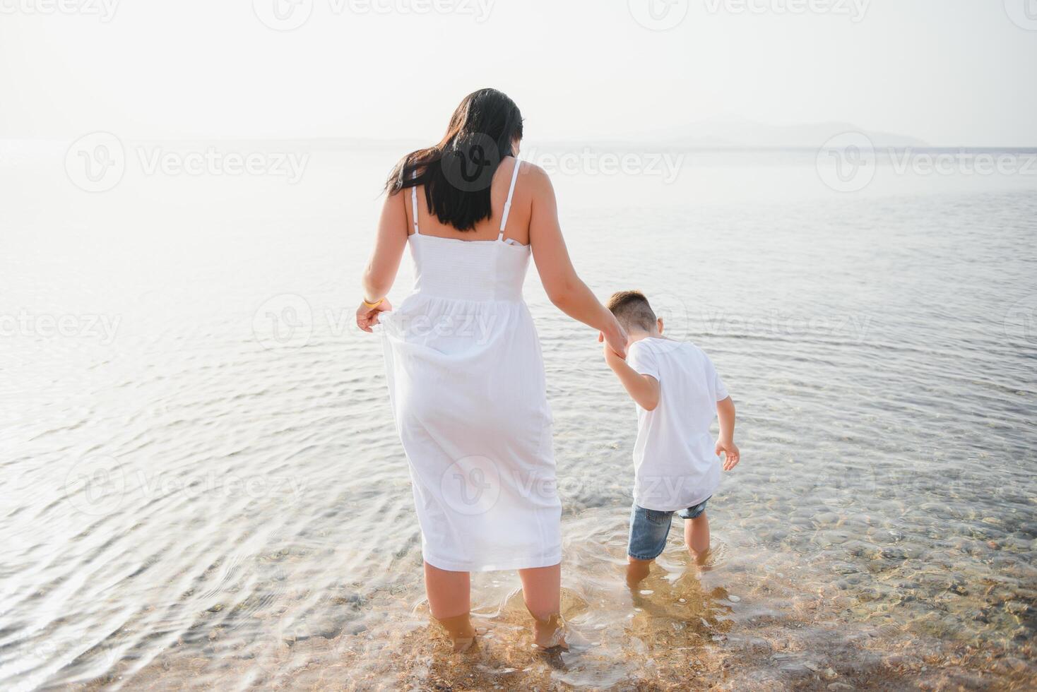 Happy mother and son walk along the ocean beach having great family time on vacation on Pandawa Beach, Bali. Paradise, travel, vacation concept photo