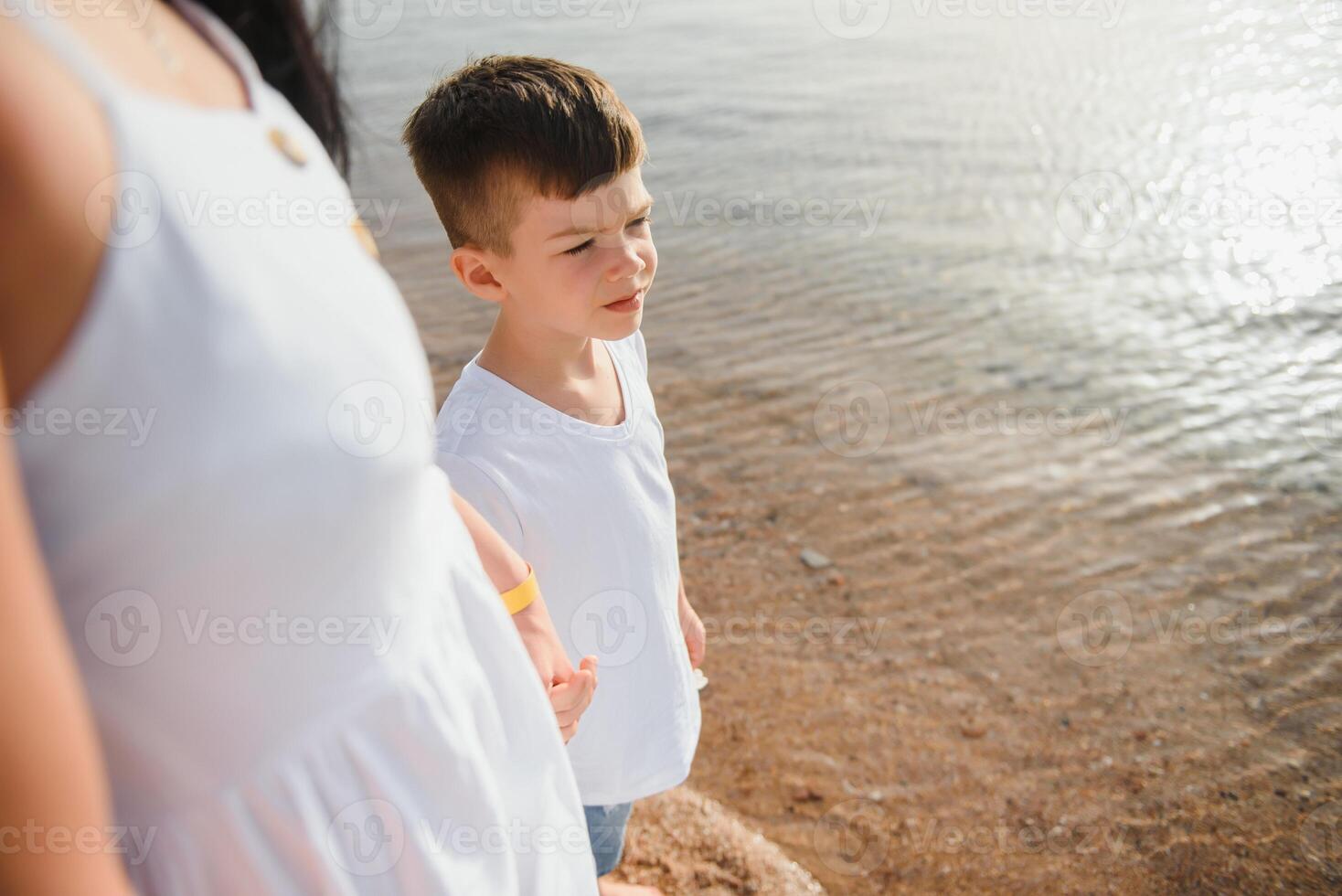 mother and son walking on sunset beach photo