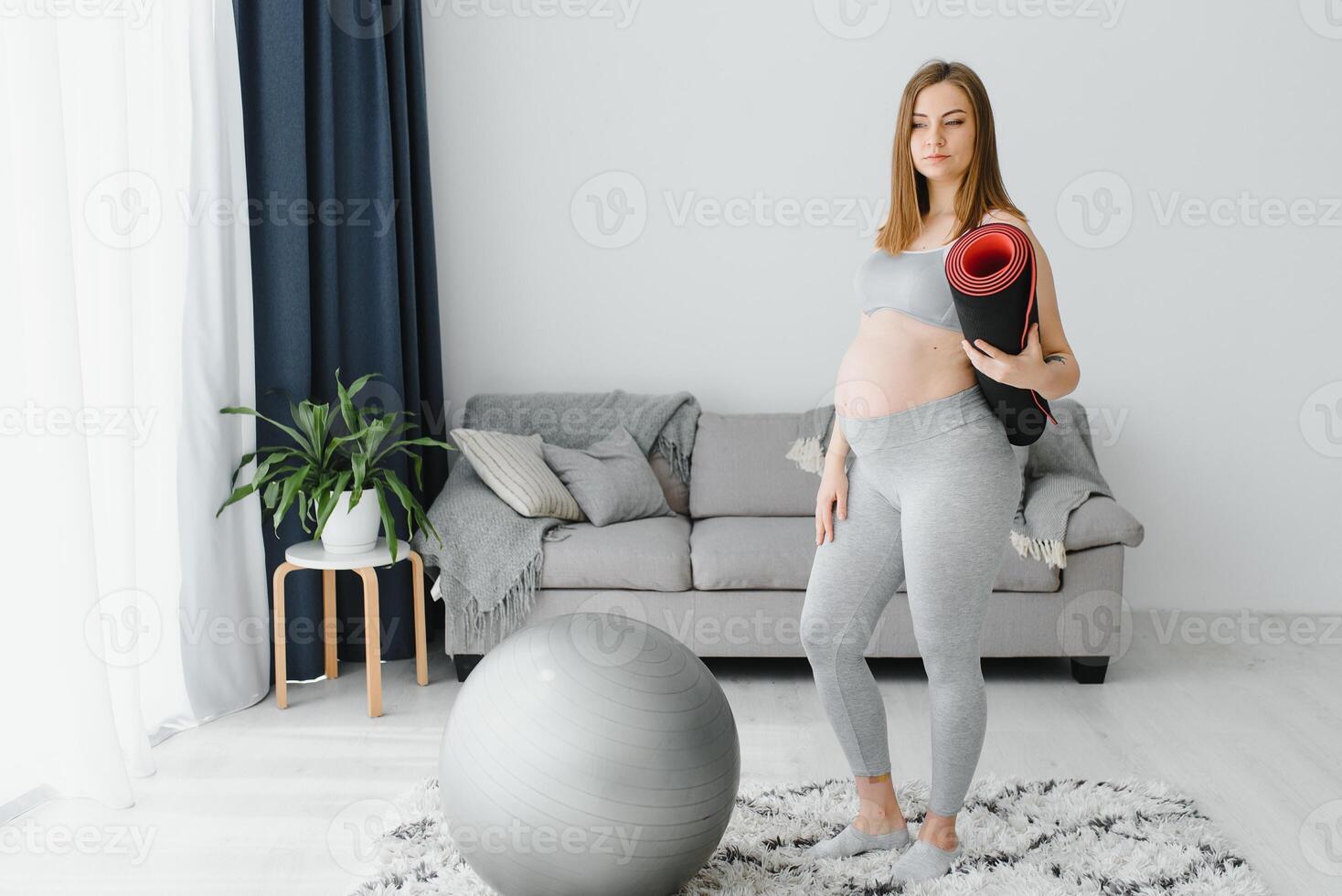 Healthy Pregnancy Yoga and Fitness concept. Young pregnant yoga woman working out in living room interior. photo