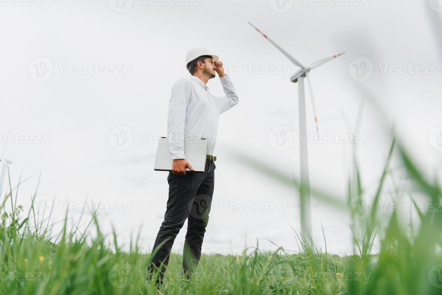 Engineer worker with laptop or computer at wind turbine power station construction site,copy space. photo