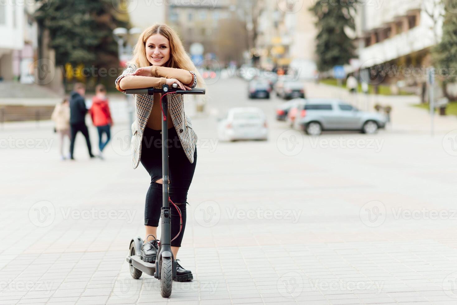 young woman on electro scooter in city. woman riding scooter in sunset light in street photo
