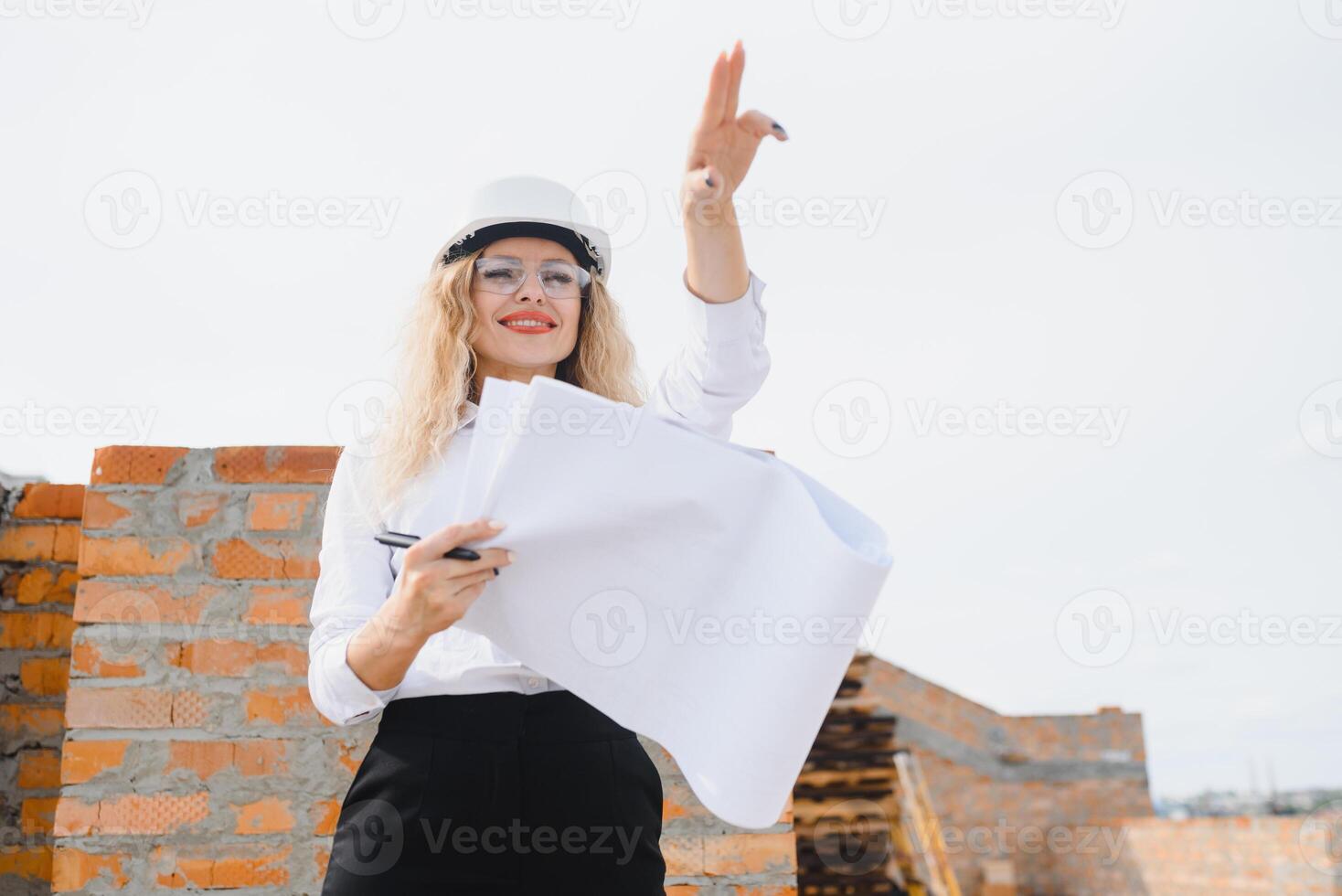 beatiful woman engineer is reviewing the plans of a construction work photo