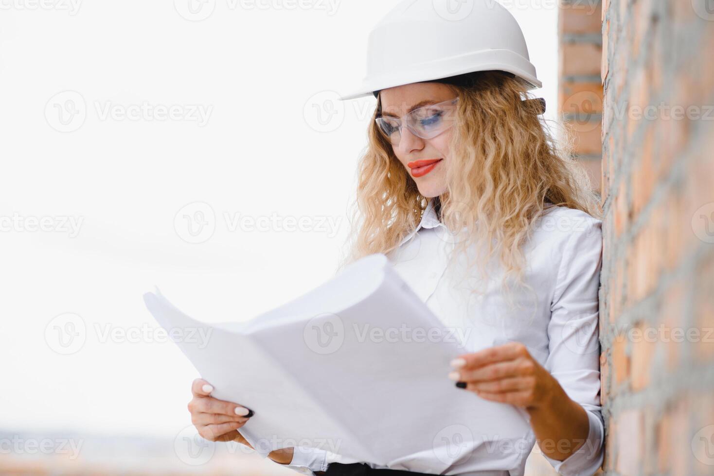 beatiful woman engineer is reviewing the plans of a construction work. photo