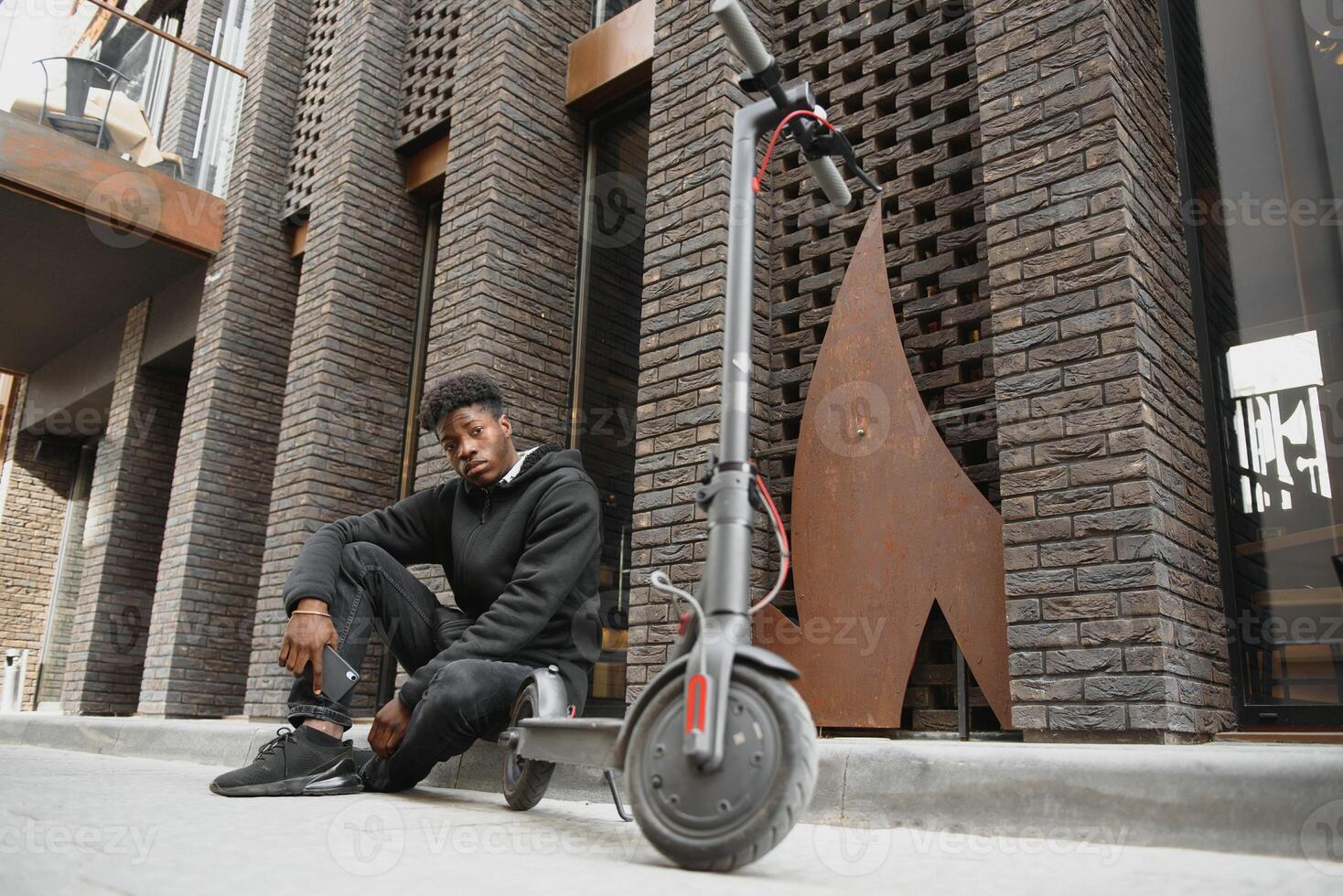 Full body side portrait happy african American man on mobile scooter on street photo