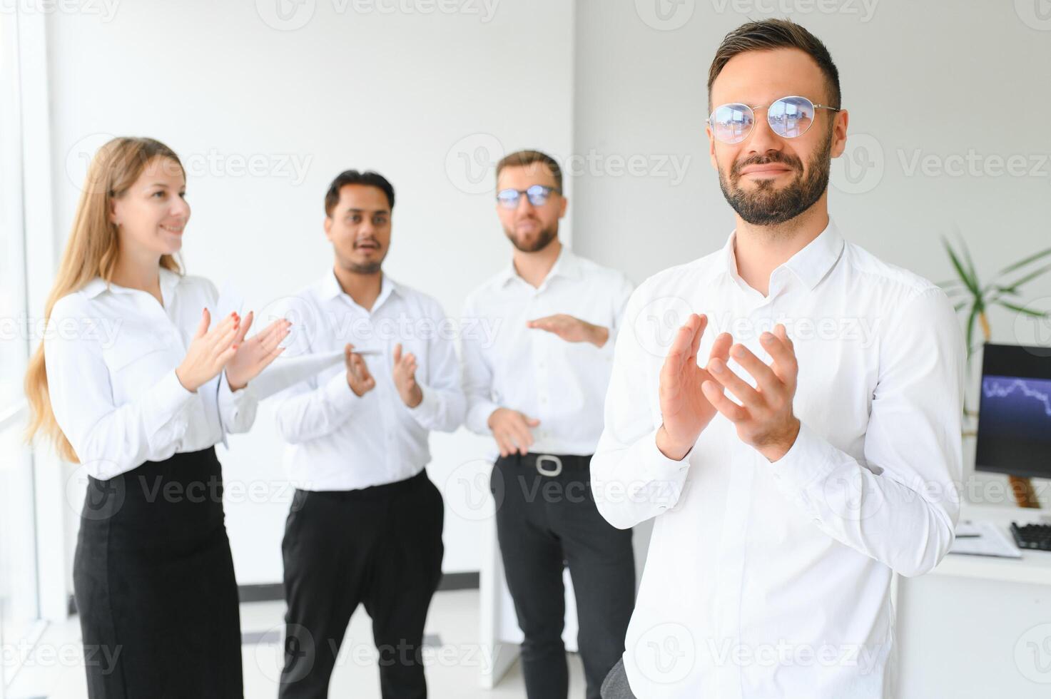 Team leader stands with coworkers in background photo