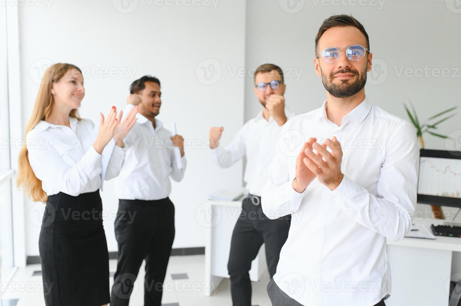 Team leader stands with coworkers in background photo