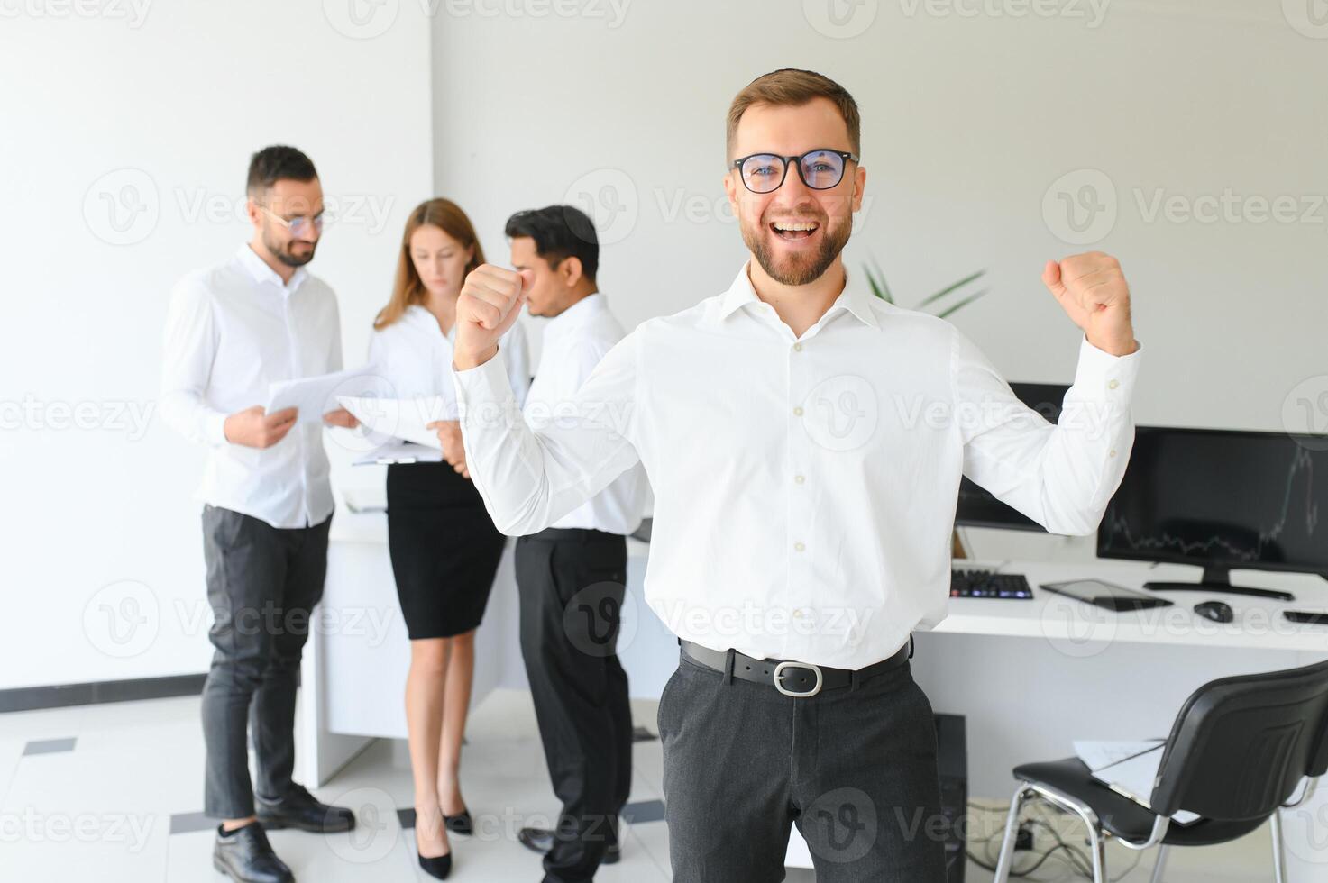 Team leader stands with coworkers in background photo