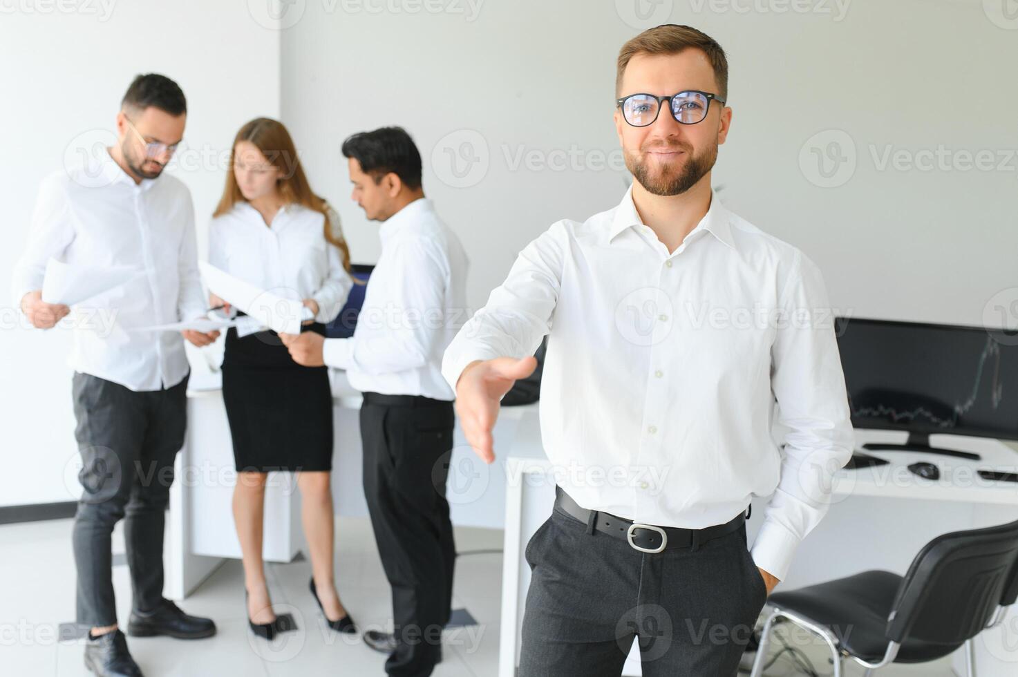 Portrait Of Young Handsome Businessman In Office With Colleagues in The Background photo