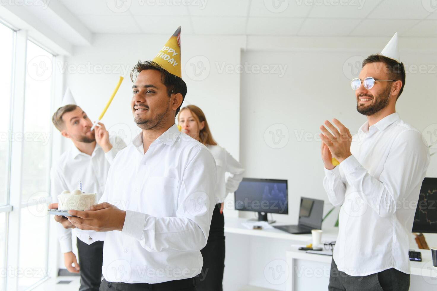 happy business team with birthday cake and gifts greeting indian male colleague at office party photo