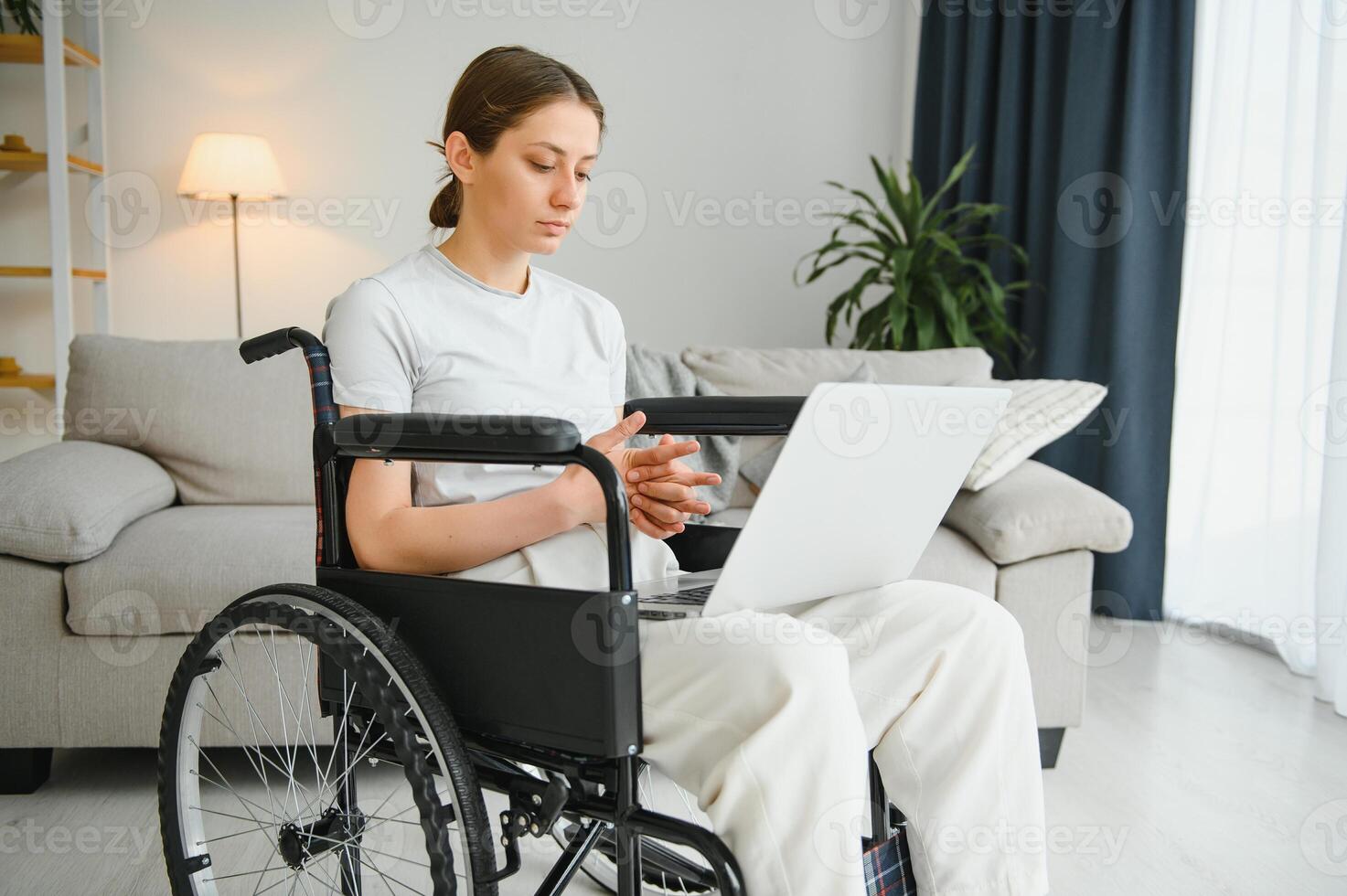 woman in a wheelchair works on the laptop PC in the home office with an assistance dog as a companion photo