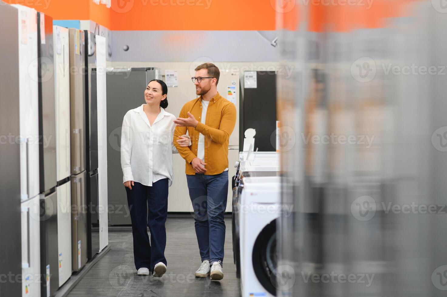 family couple buying domestic refrigerator in supermarket photo