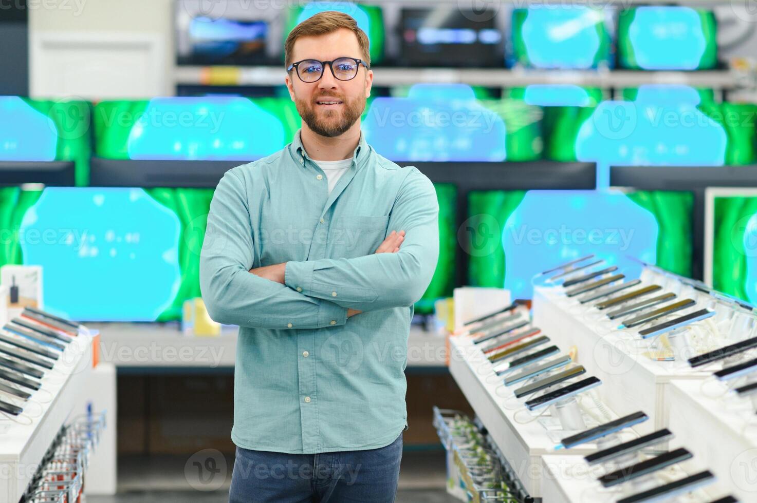 A man stands near mobile phones in an electronics store. photo