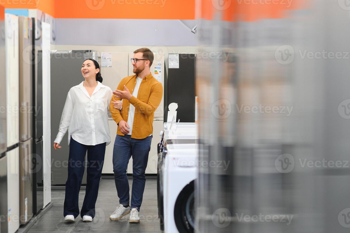 Young couple, satisfied customers choosing fridge in appliances store photo