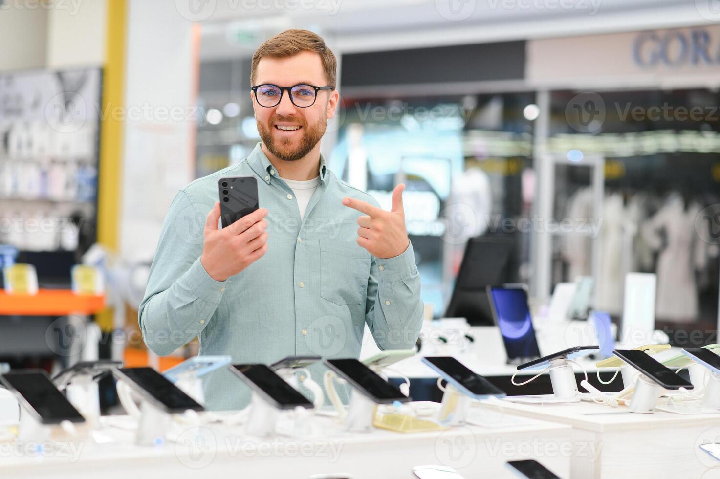happy young man choosing a new mobile in a tech store photo