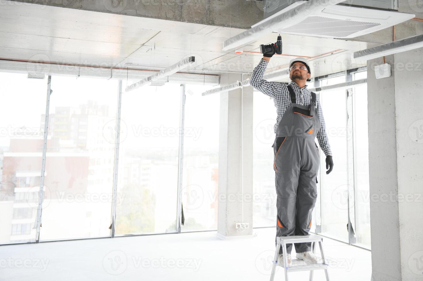 Professional technician maintaining modern air conditioner indoors. Space for text photo