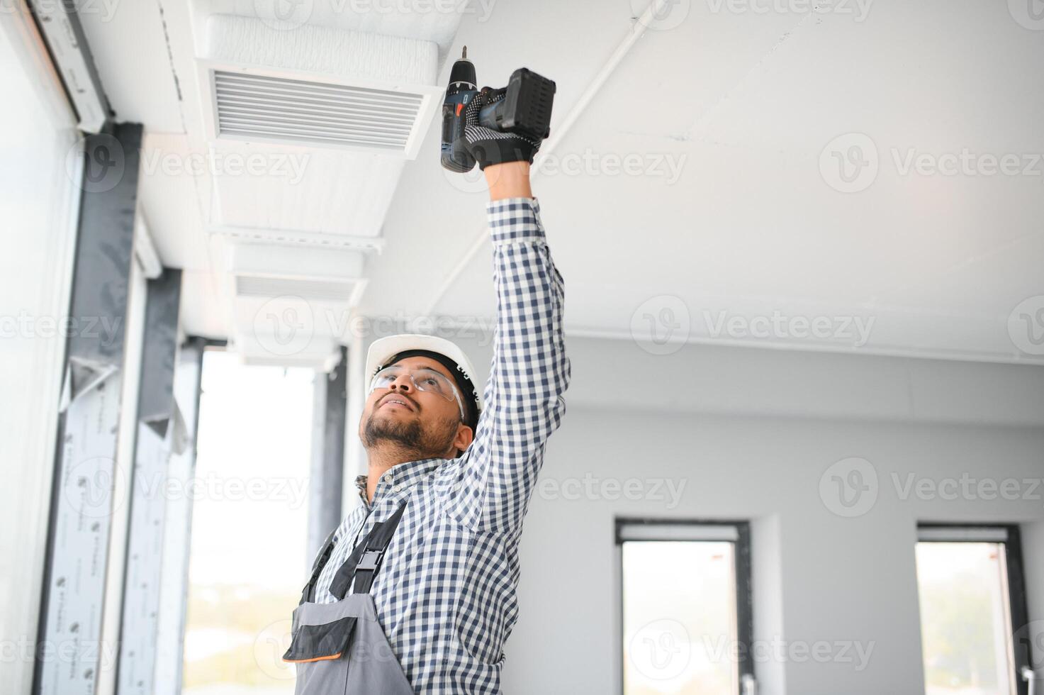 hvac indian worker install ducted pipe system for ventilation and air conditioning. copy space photo