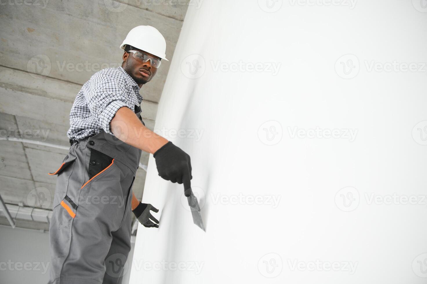 African american Plasterer in working uniform plastering the wall indoors photo