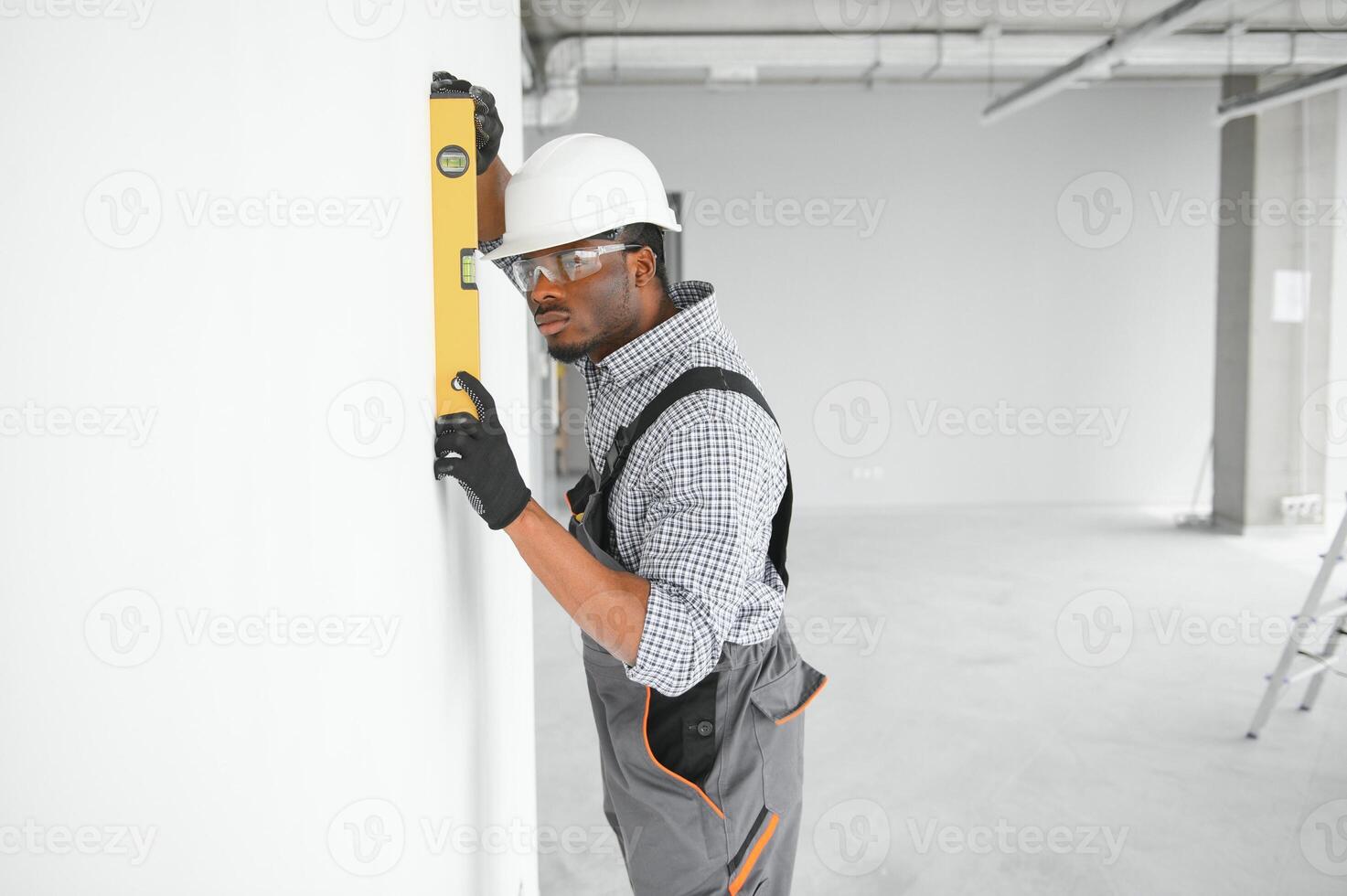 Construction worker observing and surveying wall alignment using water level photo