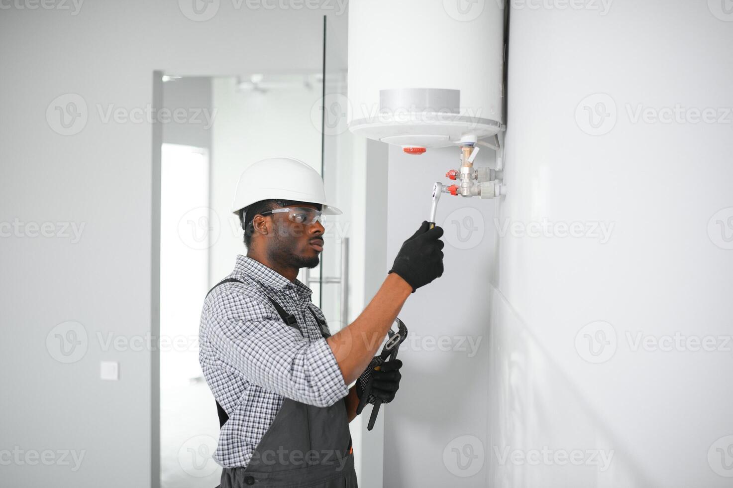 Young African Male Plumber Repairing Boiler photo