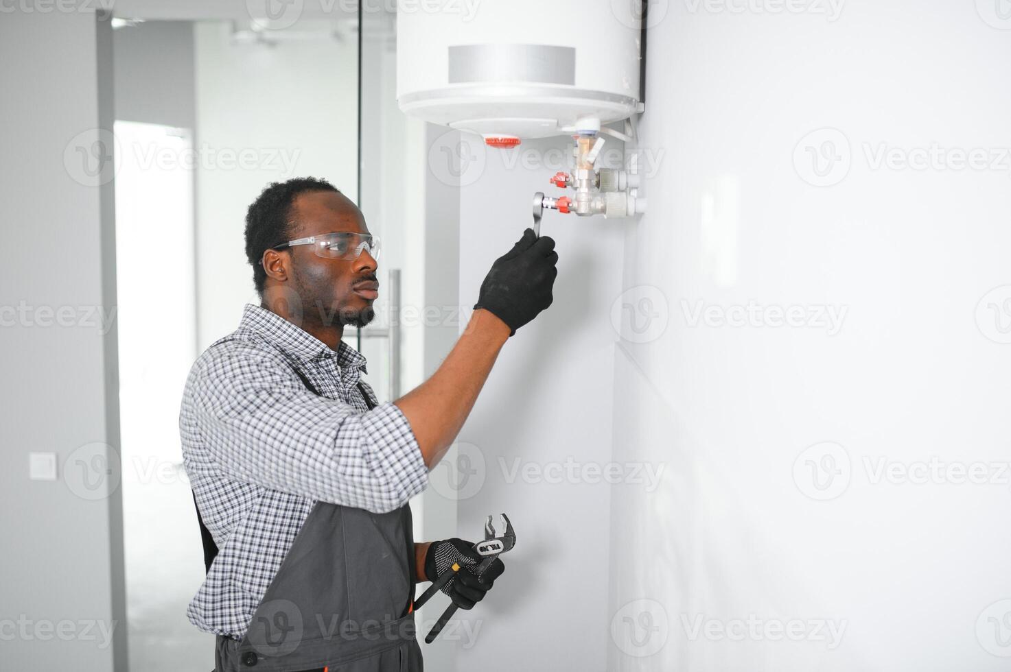 Young African Male Plumber Repairing Boiler photo