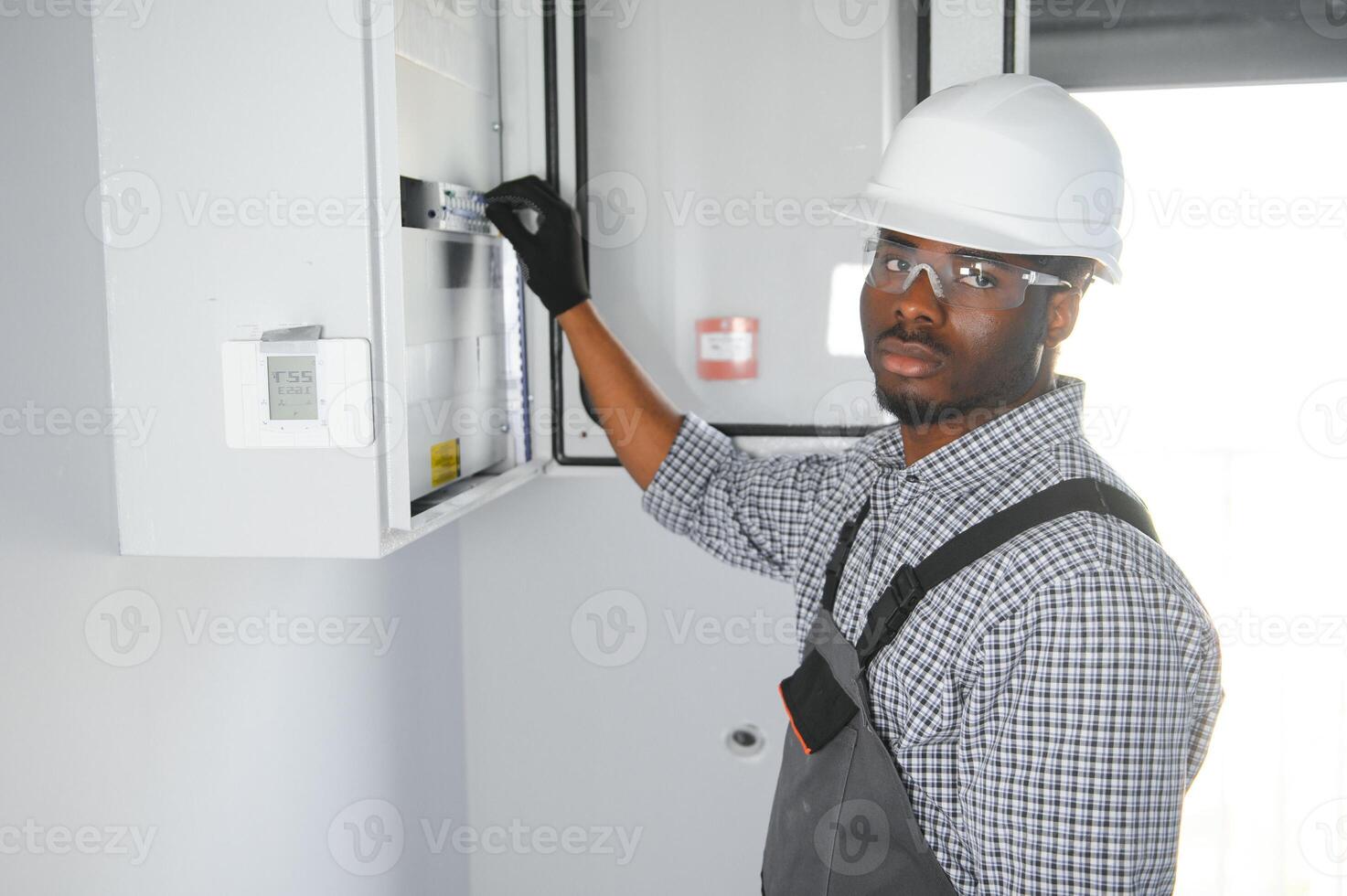 A male electrician works in a switchboard photo