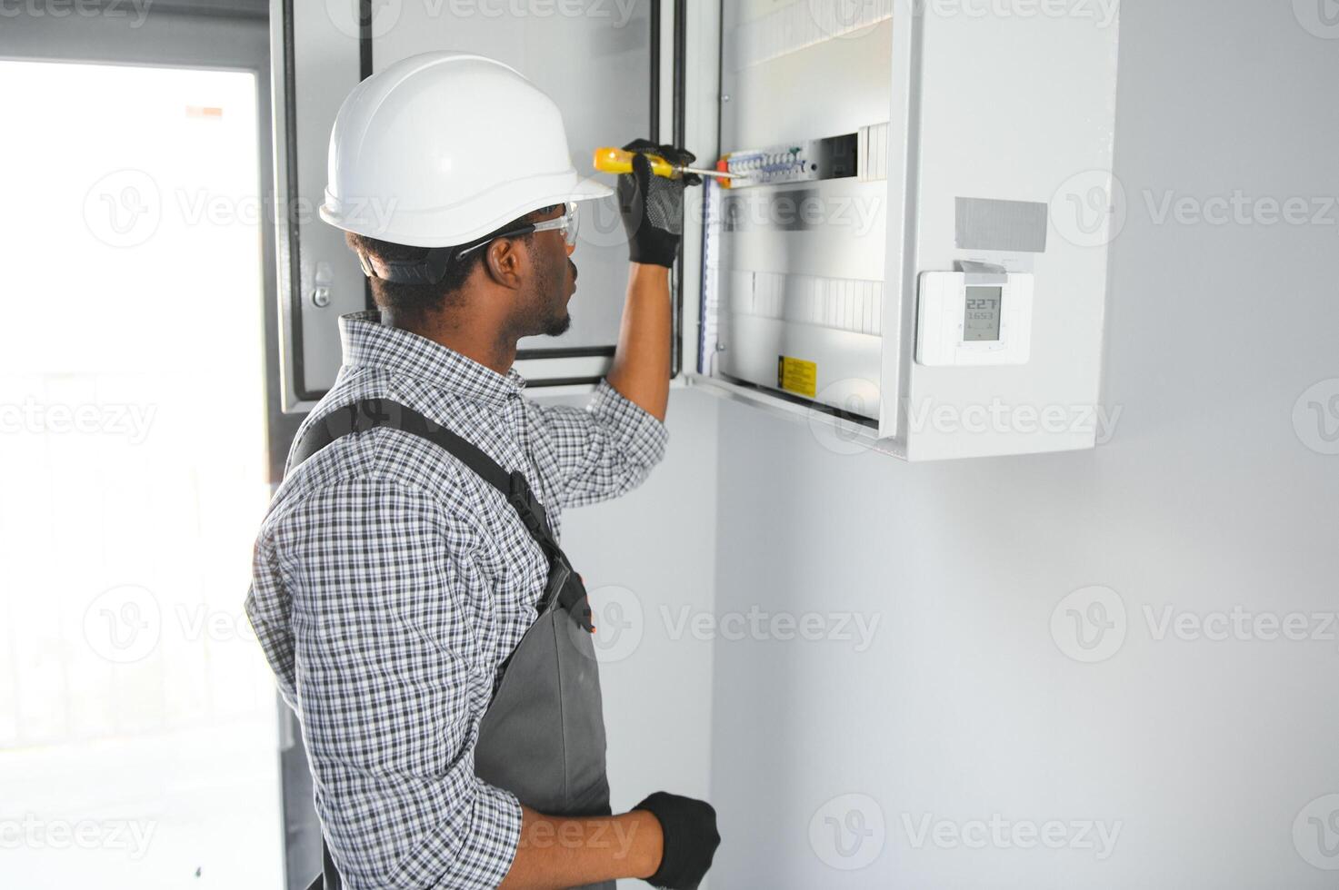 A male electrician works in a switchboard photo