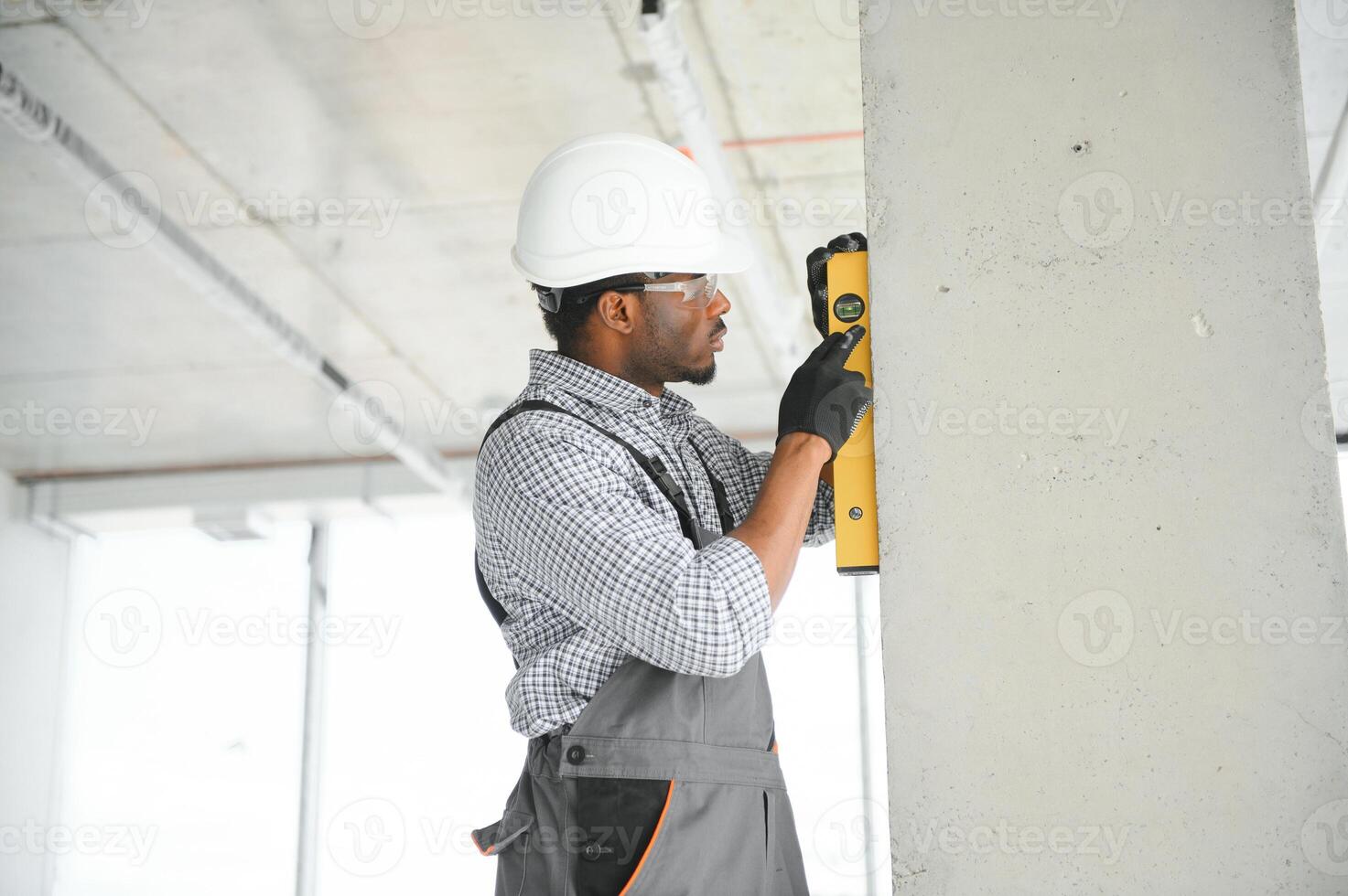 Construction worker observing and surveying wall alignment using water level photo