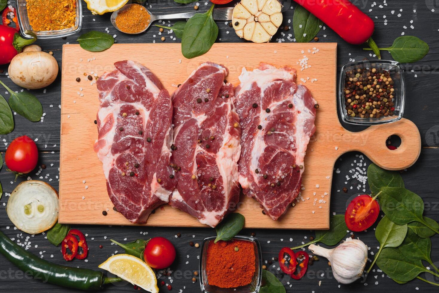 Raw pork meat on wooden cutting board at kitchen table for cooking pork steak roasted or grilled with ingredients herb and spices , Fresh pork. photo