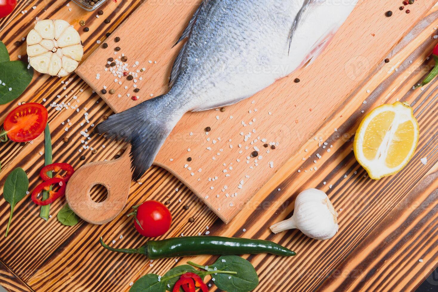 Raw dorado fish with spices cooking on cutting board. Fresh fish dorado. photo
