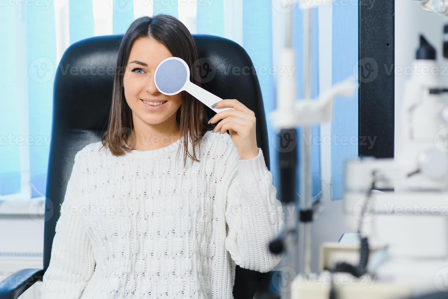 Young beautiful woman at the ophthalmologist's appointment checks her eyesight. Doctor ophthalmologist examines the patient. photo