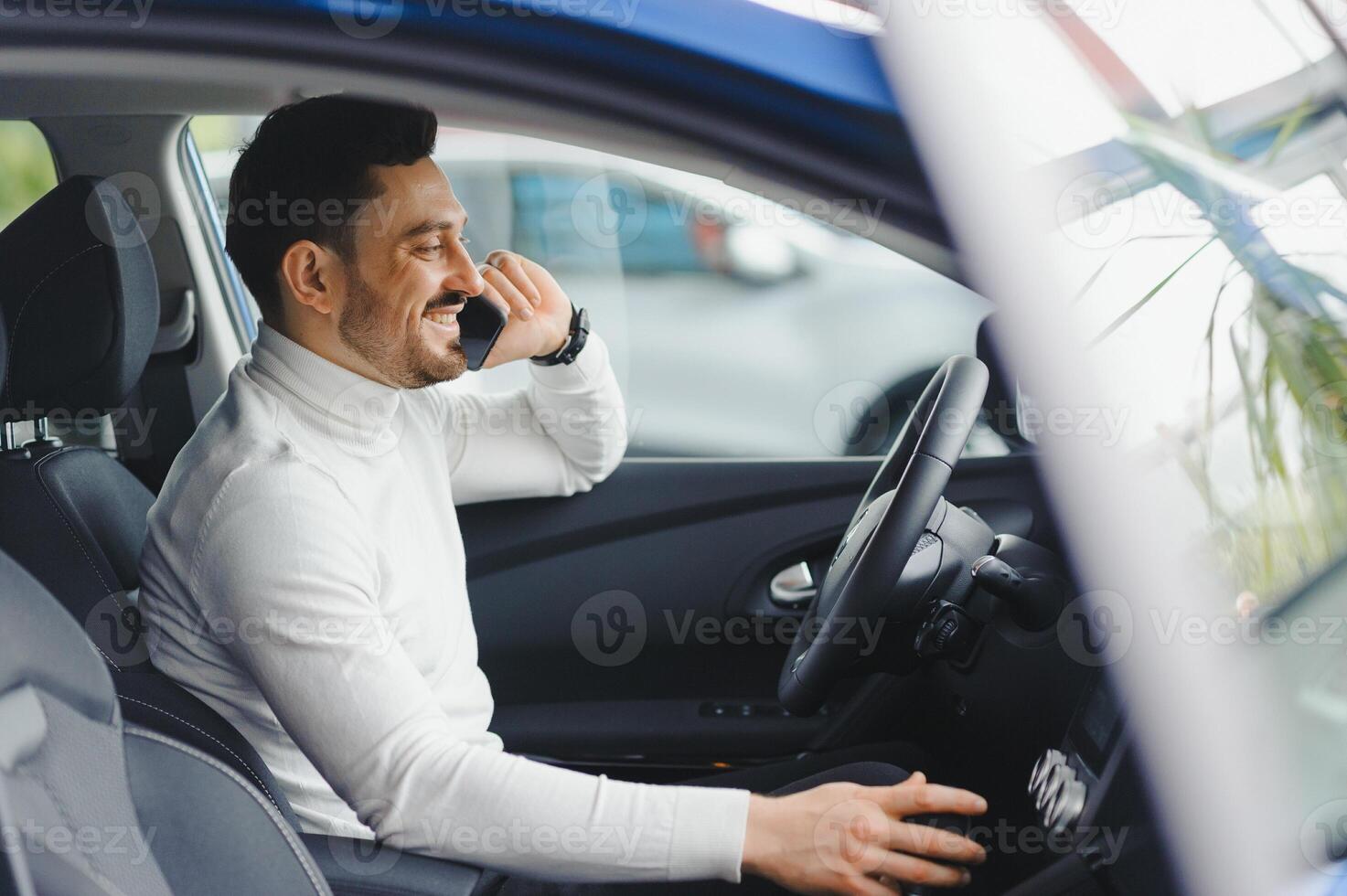 Young handsome man choosing a car in a car showroom photo