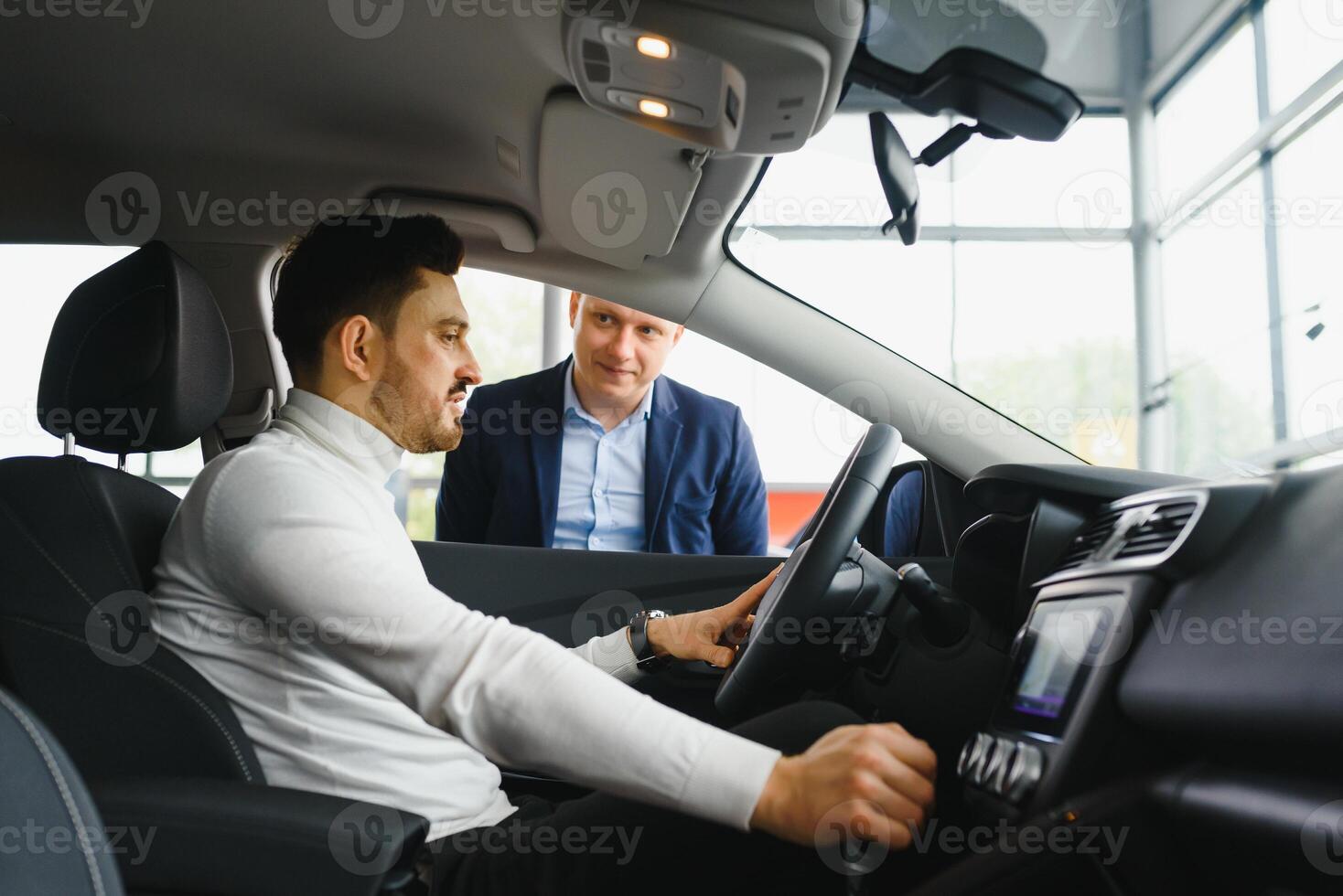 Nice business talk. Handsome young businessman talking on his smart phone and smiling while sitting on the front seat photo