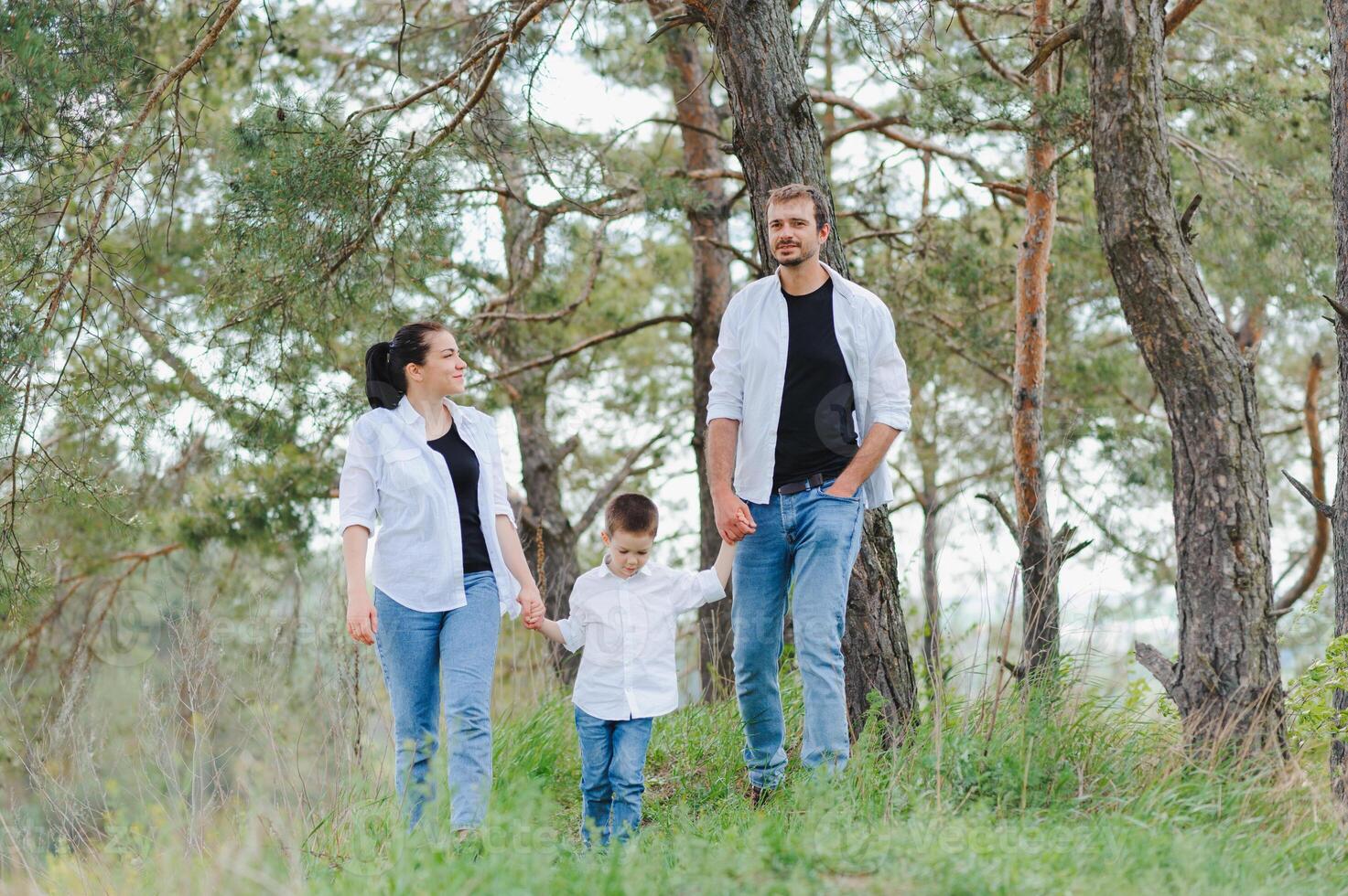 Mom, dad and son walk in the green grass. Happy young family spending time together, running outside, go in nature, on vacation, outdoors. The concept of family holiday. photo