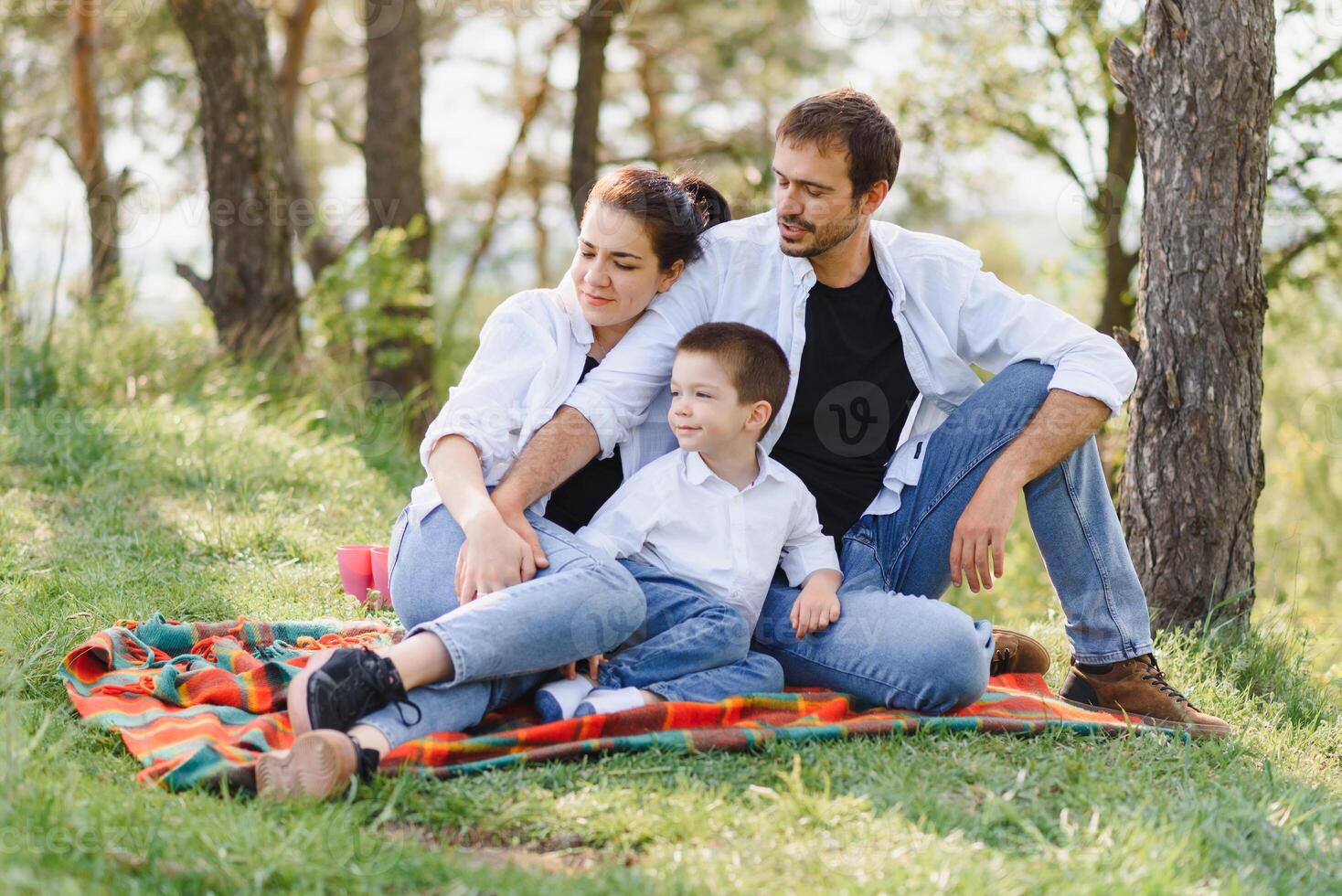 happy young family spending time outdoor on a summer day have fun at beautiful park in nature while sitting on the green grass. Happy family. photo