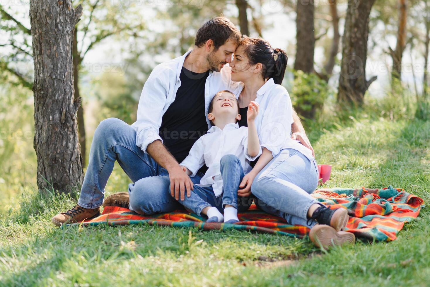 happy young family spending time outdoor on a summer day have fun at beautiful park in nature while sitting on the green grass. Happy family. photo