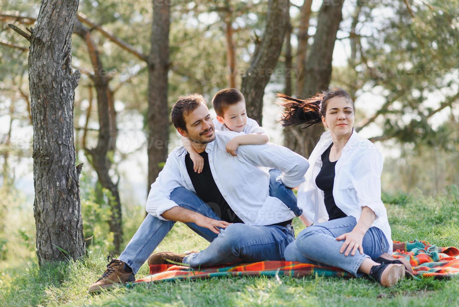 happy young family spending time outdoor on a summer day have fun at beautiful park in nature while sitting on the green grass. Happy family. photo