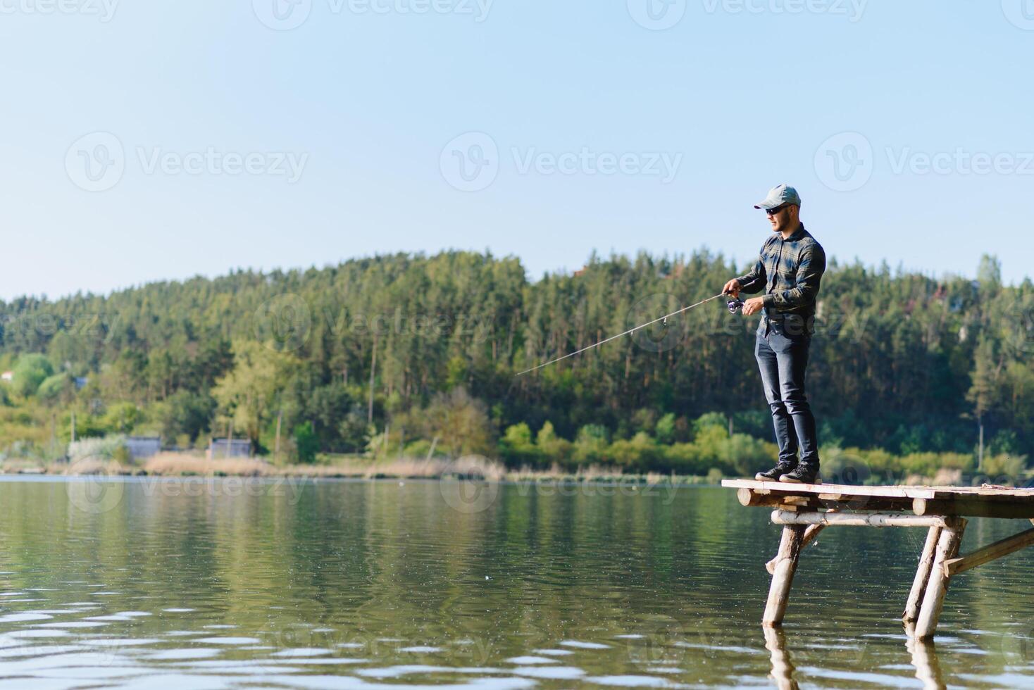 A man catches a fish on a spinning fishing in the summer photo