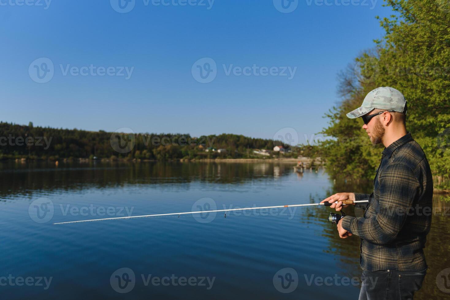 A man catches a fish on a spinning fishing in the summer photo