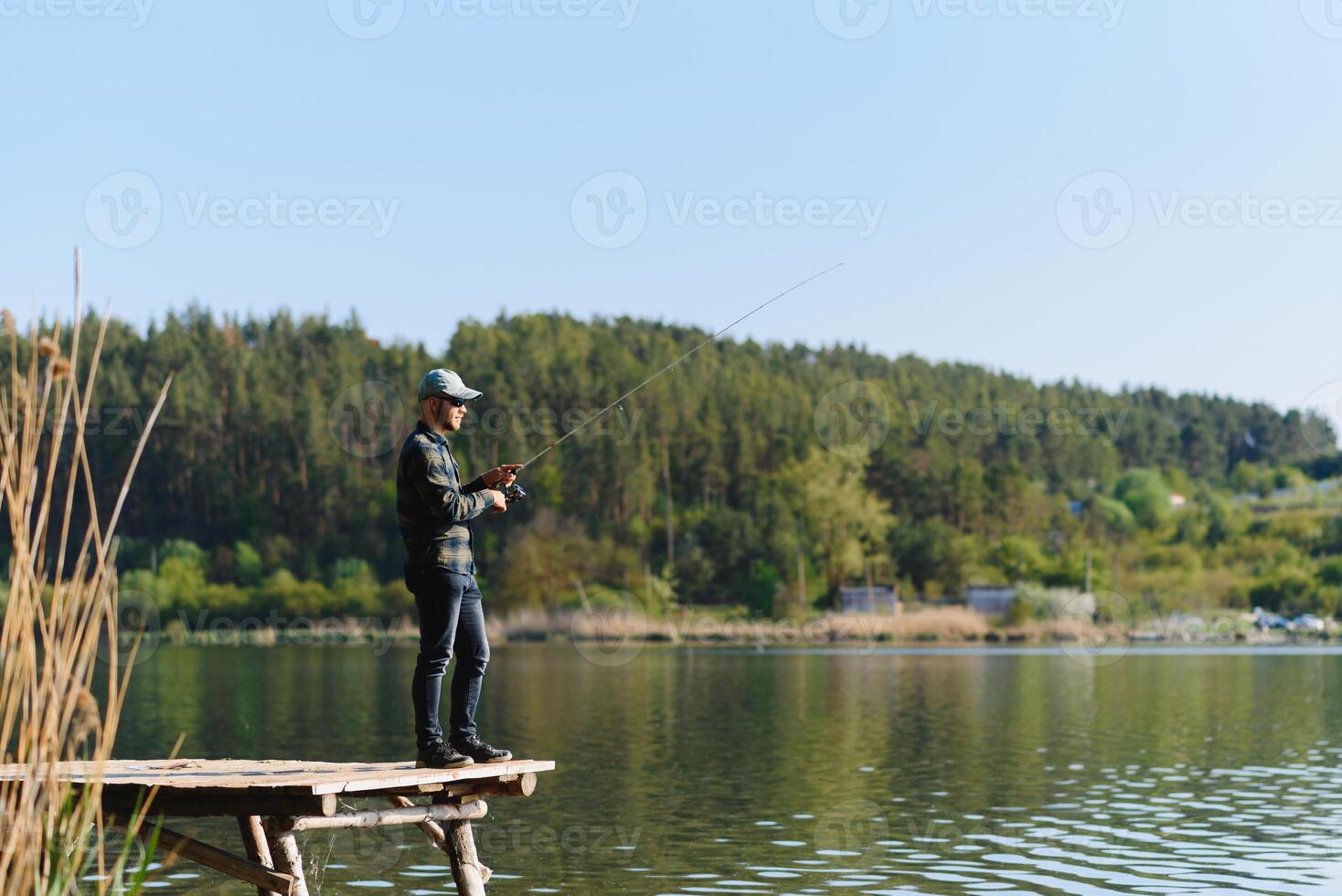 A man catches a fish on a spinning fishing in the summer photo