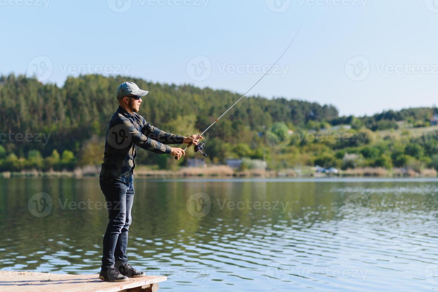 A man catches a fish on a spinning fishing in the summer photo