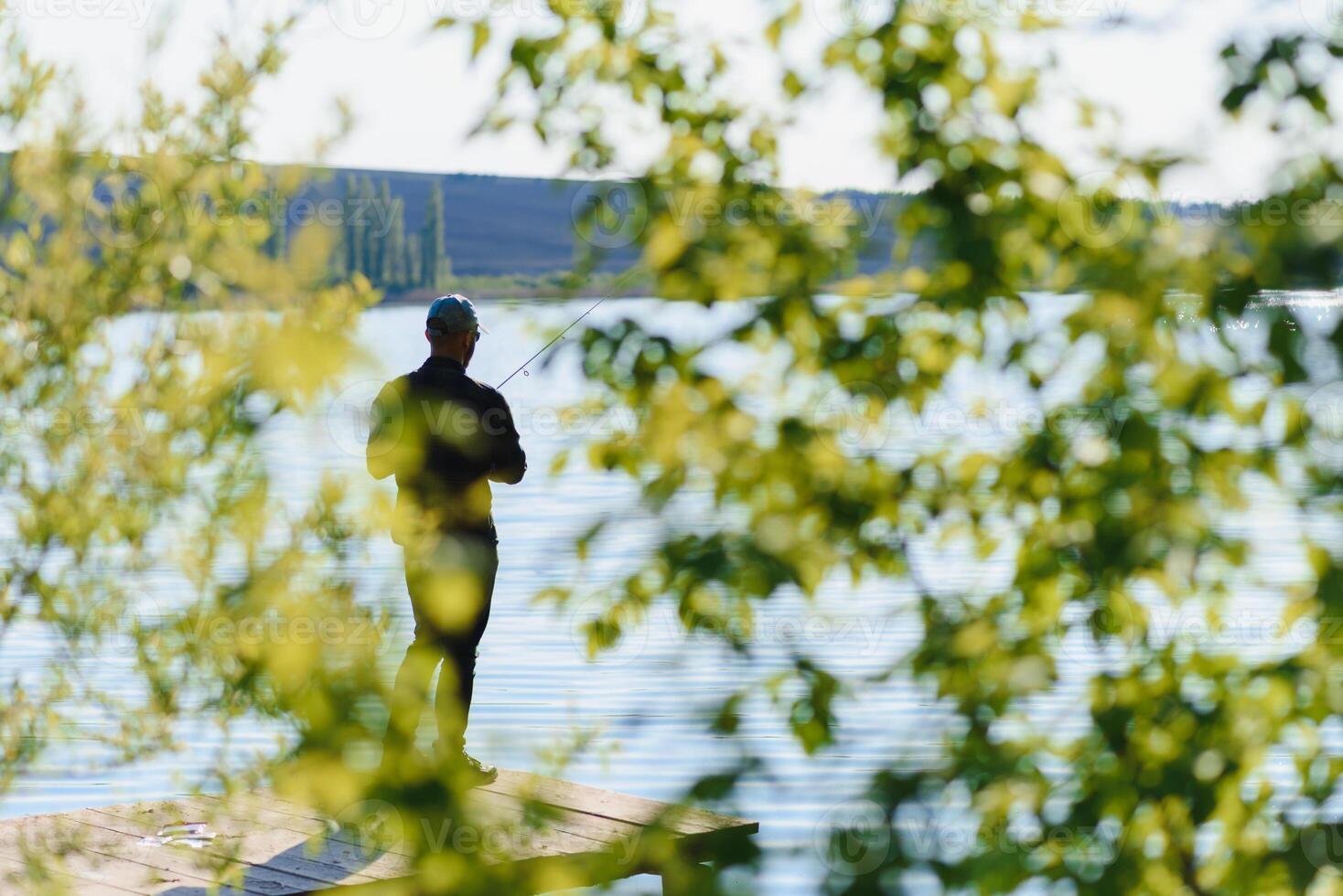 A man catches a fish on a spinning fishing in the summer photo