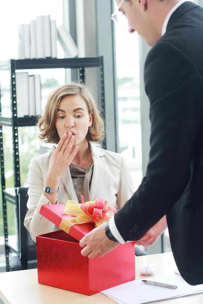 Businessman surprise and give red gift box for businesswoman in office for Birthday. Christmas,Happy new year and Valentine's Day concept photo