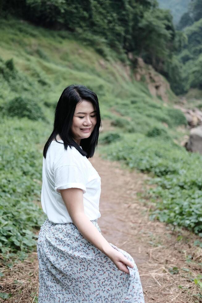 Pretty Asian woman wear white dress is smiling in tropical forest. Freedom life in nature Concept. photo